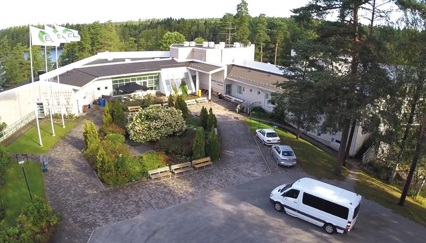 Järven rannalla olevia lomakeskuksen rakennuksia ja puutarha